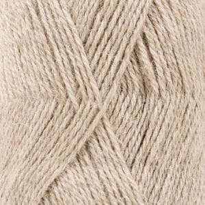Puede incluir: Una vista de cerca de un ovillo de hilo de color beige claro, que muestra la estructura de fibra trenzada y la textura suave y difusa de los hilos individuales. El hilo est&aacute; enrollado creando un patr&oacute;n diagonal repetido en la superficie.