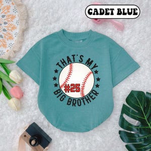 May include: A light blue short-sleeved t-shirt with a baseball graphic and the text "That's My Big Brother #25".