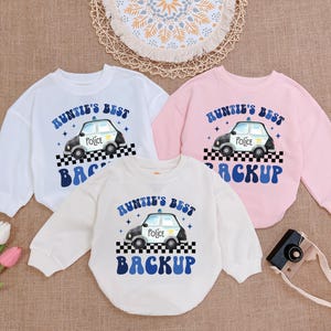 May include: Three white long-sleeved shirts with a blue and white police car graphic and the text "Auntie's Best Backup".