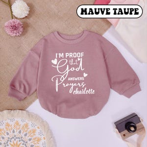 May include: Mauve taupe sweatshirt with the text "I'm proof that God answers prayers charlotte" in white lettering.
