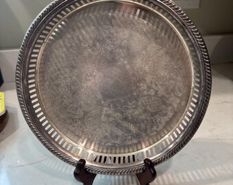 Vassoio rotondo da portata in argento placcato con bordo traforato e decorato con incisioni floreali, stile vintage.