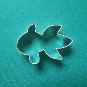 May include: A silver metal cookie cutter shaped like a stylized leaf with five points.