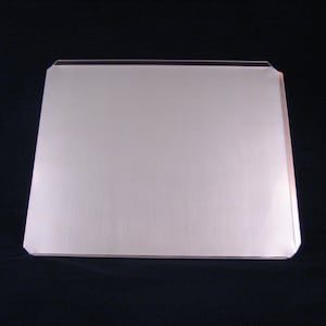 May include: A silver baking sheet with slightly rounded edges.