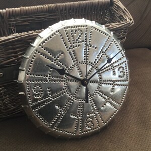 May include: A silver metal clock with black hands and Roman numeral markings. The clock face is decorated with a pattern of small holes.