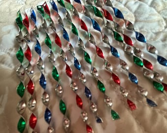 May include: A collection of metallic icicle ornaments featuring a twisted spiral design. The ornaments are finished in alternating colors of shiny red, green, blue, and silver, each with a small hole at the top for hanging purposes.