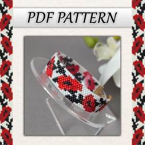 May include: A beaded bracelet with a floral pattern in red, black, and white. The bracelet is displayed on a clear stand. The words "PDF PATTERN" are at the top of the image.