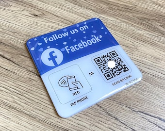 May include: Blue and white square sticker with the text "Follow us on Facebook" and a Facebook logo. The sticker also has a QR code with the text "SCAN QR CODE ID: 9CC3AA" and a symbol of a phone with the text "NFC TAP PHONE"