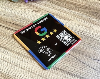 May include: Black square sticker with rounded corners, featuring a Google logo, five gold stars, a QR code, and the text "Review us on Google". The sticker has a colorful border with red, yellow, blue, and green.