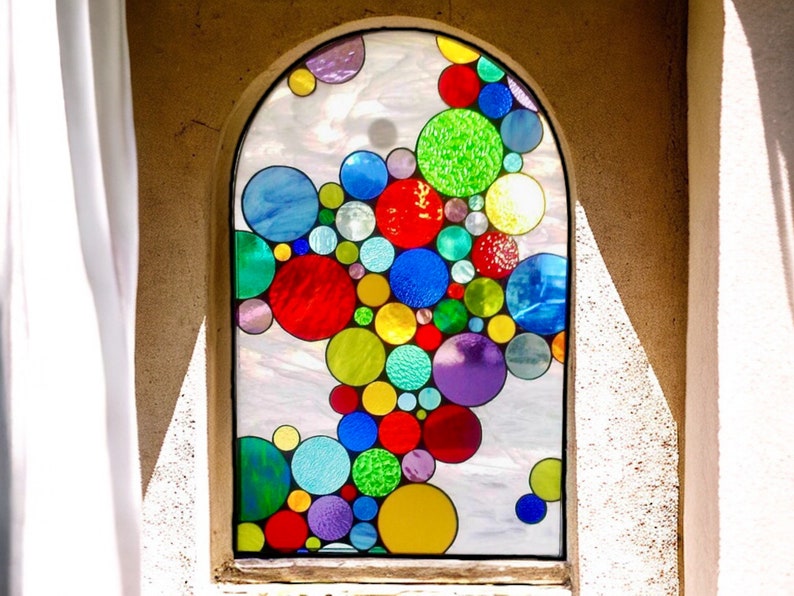 May include: A stained glass window with a design of colorful circles in various sizes and shades of red, blue, green, yellow, and purple.