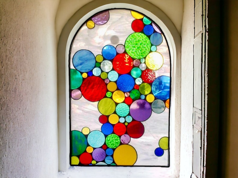 May include: A stained glass window with a design of colorful circles in various shades of red, blue, green, yellow, and purple.
