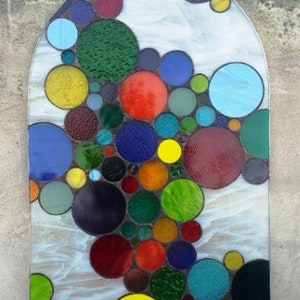 May include: A stained glass window with a design of colorful circles in shades of red, blue, green, yellow, and purple.