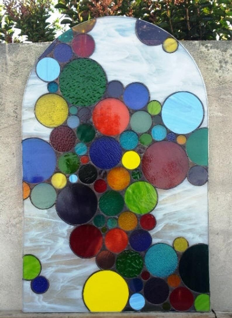 May include: A stained glass window with a design of colorful circles in shades of red, blue, green, yellow, and purple.