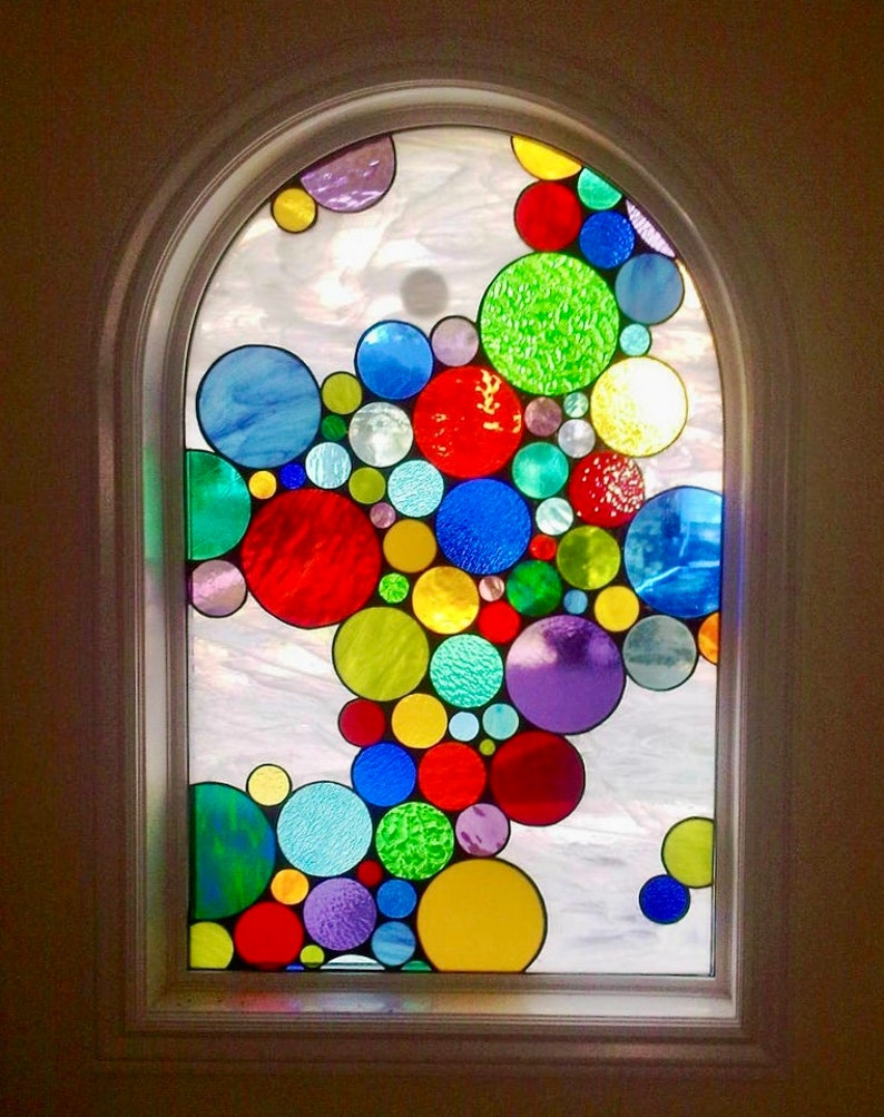 May include: A stained glass window with a design of colorful circles in various sizes. The circles are arranged in a cascading pattern, creating a whimsical and vibrant effect.