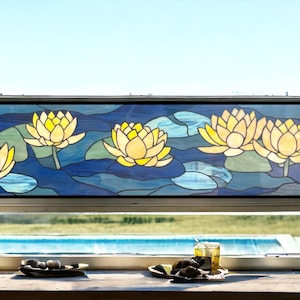 May include: A stained glass window panel depicting yellow water lilies on a blue and green background. The panel is framed in black and is set in a window with a view of a swimming pool.