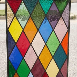 May include: A stained glass window with a diamond pattern in various colors, including red, blue, green, yellow, and orange.