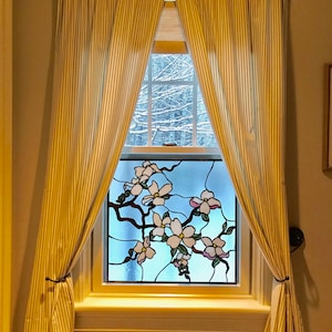 May include: A window with yellow and white striped curtains, featuring a stained glass panel depicting a branch of white flowers.