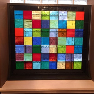 May include: A stained glass window with a grid of colorful squares in shades of red, blue, green, yellow, and purple.