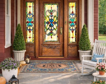 May include: A wooden front door with stained glass panels and a decorative rug. The door is flanked by potted evergreen trees and pumpkins. A white rocking chair and small table with flowers are on the porch.