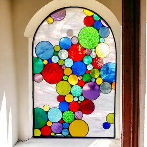 May include: A stained glass window with a colorful design of overlapping circles in shades of red, blue, green, yellow, and purple.