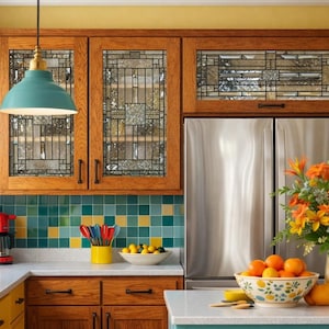 May include: A kitchen with wooden cabinets, a stainless steel refrigerator, and teal pendant lights. The backsplash features teal, yellow, and white tiles. A bowl of oranges and a vase of flowers sit on the countertop.