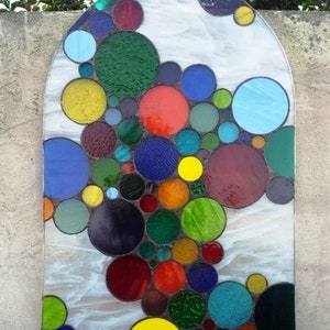 May include: A stained glass window featuring a colorful abstract design of overlapping circles in shades of red, blue, green, yellow, and purple.