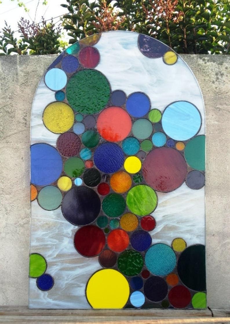 May include: A stained glass window featuring a colorful abstract design of overlapping circles in shades of red, blue, green, yellow, and purple.