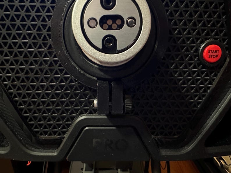 May include: Close-up of a black exercise bike with a silver and black sensor, a black adjustment knob, and a red "START STOP" button.