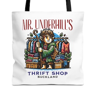 Può includere: Una borsa di tela bianca con un'illustrazione colorata di un personaggio che tiene un bastone davanti a un appendiabiti. Il testo "Mr. Underhill's Thrift Shop Buckland" è stampato sulla borsa.