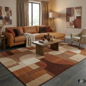 May include: A living room scene featuring a large, brown leather sectional sofa with several throw pillows. A geometric patterned rug in shades of brown and beige covers the floor. A wooden coffee table and artwork complete the warm, inviting space.