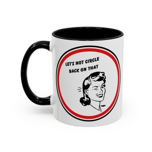 May include: White ceramic mug with a black handle and black rim. The mug has a red circle with a black border around a black and white illustration of a woman winking. The text "Let's not circle back on that" is printed in black inside the circle.