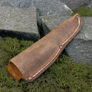 Brown Crazy Horse leather knife sheath with stitched edges, minimalist leather knife cover shown outdoors