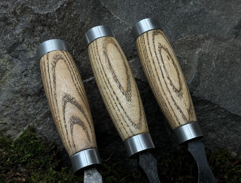 May include: Three wooden handled tools with silver metal caps and black metal blades. The handles are made of light brown wood with dark brown grain patterns.
