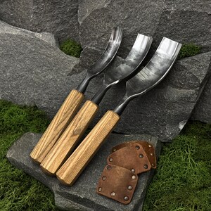 May include: Three wood carving gouges with curved metal blades and light brown wooden handles, accompanied by three small, square-shaped brown leather blade guards featuring metal rivets, arranged together for woodworking tasks.