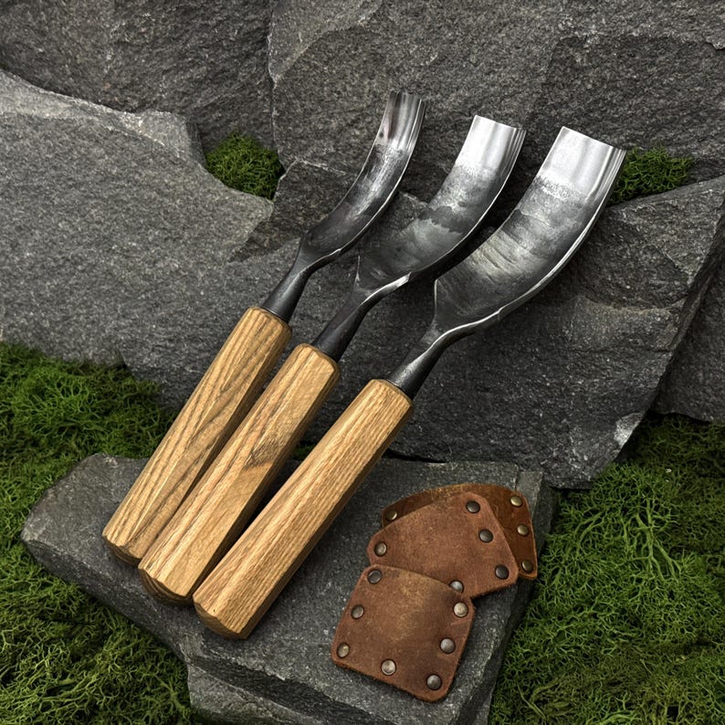 May include: Three wood carving gouges with curved metal blades and light brown wooden handles, accompanied by three small, square-shaped brown leather blade guards featuring metal rivets, arranged together for woodworking tasks.