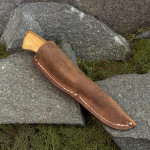 Universal leather knife sheath displayed on stone surface, handcrafted leather knife holder for bushcraft use