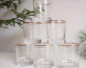 May include: A stack of seven clear drinking glasses with gold rims. The glasses have a short, cylindrical shape and a delicate etched design. The gold rims add a touch of elegance to the glassware. The glasses are arranged in a pyramid shape.
