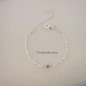 May include: A delicate silver chain bracelet with a small star charm. The chain is a simple, linked design.