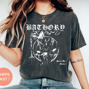 Op de afbeelding: Donkergrijs t-shirt met de bandnaam "BATHORY" in witte gotische letters boven een witte afbeelding. De afbeelding toont een pentagram en andere symbolen. De tekst "Satan My Master" staat eronder.