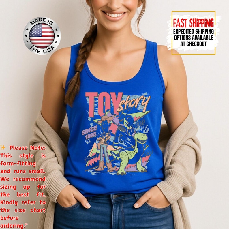 Op de afbeelding: Een blauwe tanktop met de woorden "Toy Story" in roze en geel, met karakterafbeeldingen. De tanktop heeft een ronde halslijn. De tekst "Since 1995" is ook zichtbaar. Gemaakt in de VS.