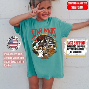 Op de afbeelding: Zeegroen T-shirt met een Star Wars-afbeelding met tekenfilmfiguren. De afbeelding bevat de tekst "STAR WARS" in het rood. Het shirt is een Bella+Canvas Tee, Comfort Colors Tee of Gildan Sweatshirt & Hoodie.