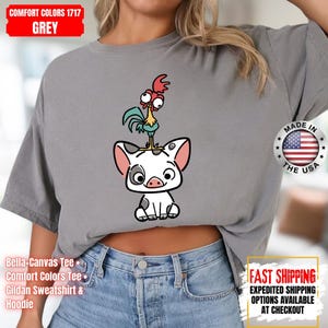 K&ouml;nnte beinhalten: Graues Comfort Colors T-Shirt mit einem Cartoon-Schwein und Hahn-Design. Das Shirt tr&auml;gt den Text "MADE IN THE USA" und "FAST SHIPPING". Es ist ein Bella-Canvas Tee, Comfort Colors Tee oder Gildan Sweatshirt & Hoodie.