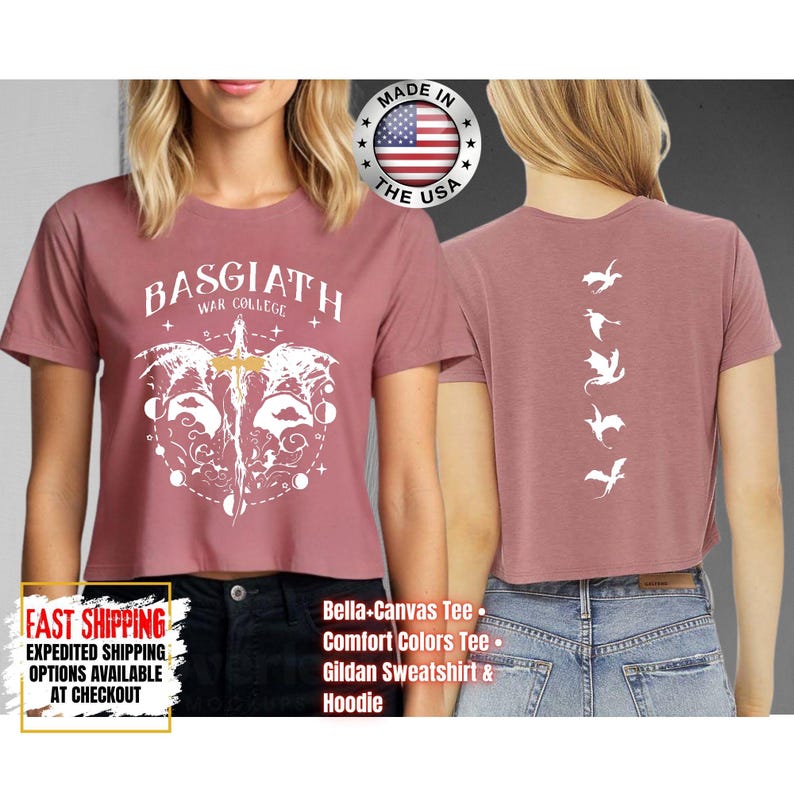 Puede incluir: Top corto rosa polvoriento con el texto "BASGIATH WAR COLLEGE" y un gr&aacute;fico blanco de una espada y alas. La parte posterior de la camisa presenta una fila vertical de siluetas de dragones blancos. Hecho en los EE. UU.
