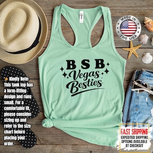May include: A light green racerback tank top with the text "BSB Vegas Besties" in black script. The tank top is made in the USA. A straw hat, flip-flops, and sunglasses are next to the tank top.