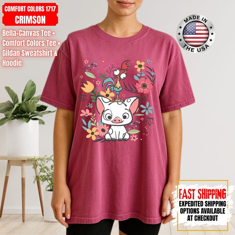 May include: Crimson Comfort Colors tee with a graphic of a pig, rooster, and flowers. The shirt has short sleeves and a crew neck. The text "MADE IN THE USA" is printed on the shirt. Part of the Bella-Canvas Tee, Comfort Colors Tee, and Gildan Sweatshirt & Hoodie collection.
