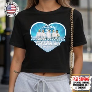 May include: Black crop top featuring a heart-shaped graphic with the text "Into the Millennium Backstreet Boys." The graphic includes a photo of the band members. The shirt is made in the USA.