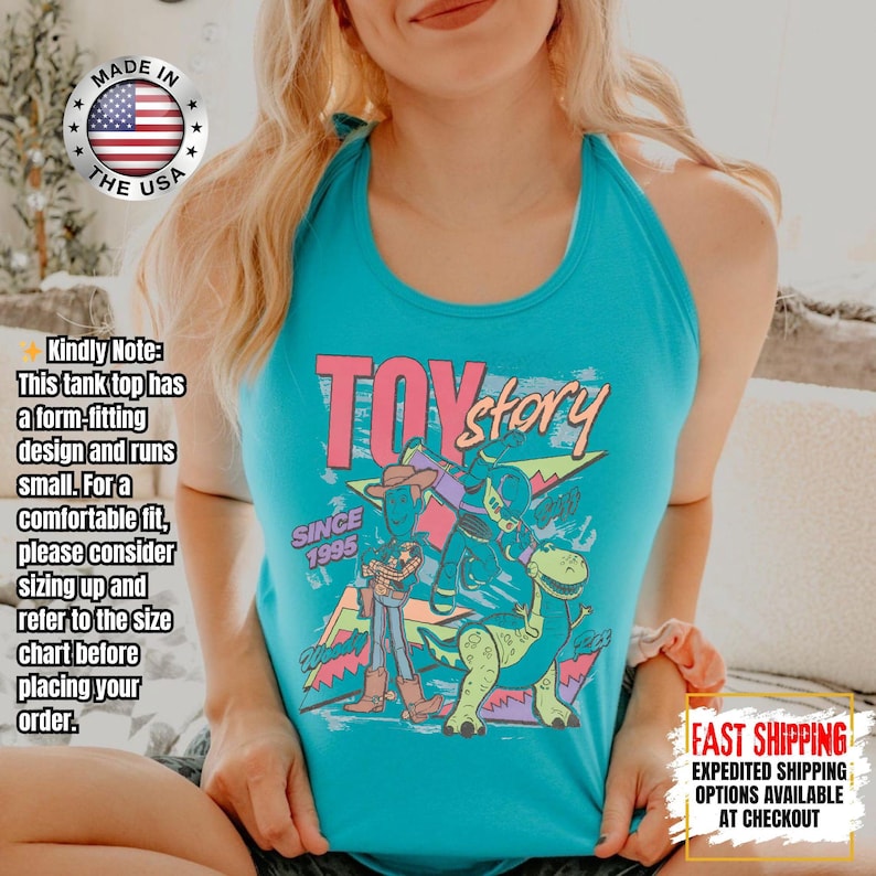 Op de afbeelding: Een turquoise tanktop met een kleurrijke afbeelding uit de film "Toy Story". Het ontwerp bevat de tekst "TOY STORY" en "SINCE 1995", samen met afbeeldingen van personages. Gemaakt in de VS.