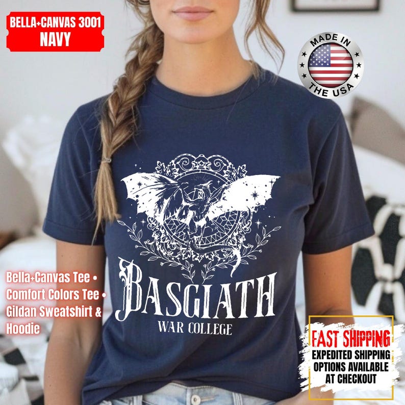 Op de afbeelding: Marineblauw t-shirt met een witte afbeelding van een gevleugeld wezen en de tekst "BASGIATH WAR COLLEGE". Het shirt heeft ook de tekst "BELLA-CANVAS 3001 NAVY" en "MADE IN THE USA".