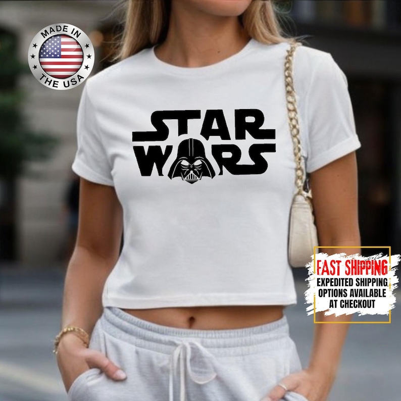 Puede incluir: Top corto blanco con la inscripci&oacute;n negra "STAR WARS" y un casco de Darth Vader incorporado. Fabricado en EE. UU.