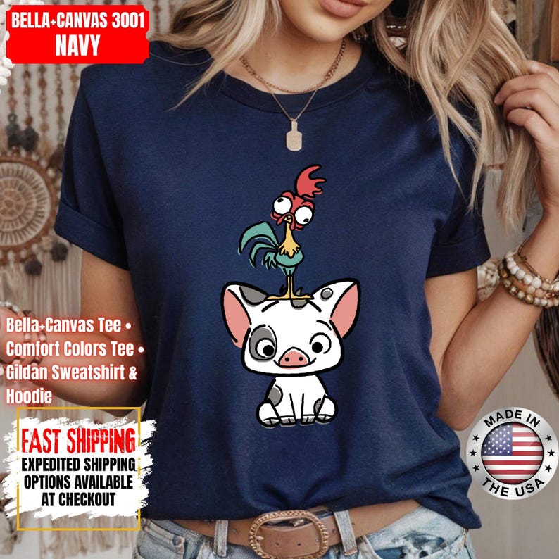 K&ouml;nnte beinhalten: Marineblaues T-Shirt mit einer Cartoon-Illustration eines Schweins und eines Hahns. Das Schwein ist wei&szlig; mit schwarzen Flecken und rosa Ohren und Schnauze. Der Hahn ist gr&uuml;n, gelb und rot. Das Shirt hat den Text "BELLA-CANVAS 3001 NAVY".