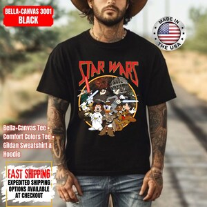 Op de afbeelding: Zwart T-shirt met een Star Wars-afbeelding met tekenfilmfiguren. De tekst "STAR WARS" is in rood en geel. Het shirt heeft ook de tekst "BELLA-CANVAS 3001 BLACK".